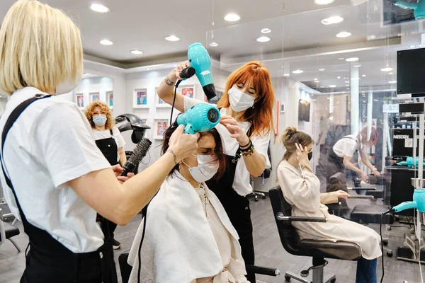 Dos peluqueros secando el cabello de un cliente en la peluquería. —  Fotos de Stock