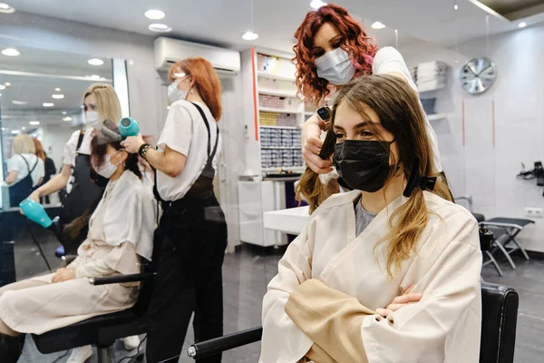 Ung kvinna med en ansiktsmask får en ny frisyr på frisören. — Stockfoto