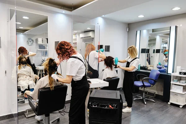 Peluqueros trabajando con clientes en la peluquería. —  Fotos de Stock