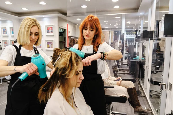 Fryzjerzy robi fryzurę dla młodej kobiety w salonie piękności. — Zdjęcie stockowe