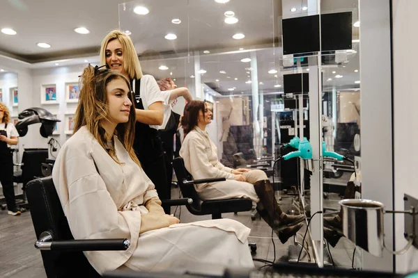 Mujeres consiguiendo un peinado por los peluqueros en el salón de belleza. —  Fotos de Stock
