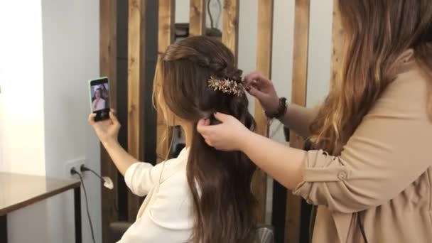 Narzeczona nagrywa wideo lub robi selfie za pomocą smartfona, przygotowując włosy do ślubu. — Wideo stockowe