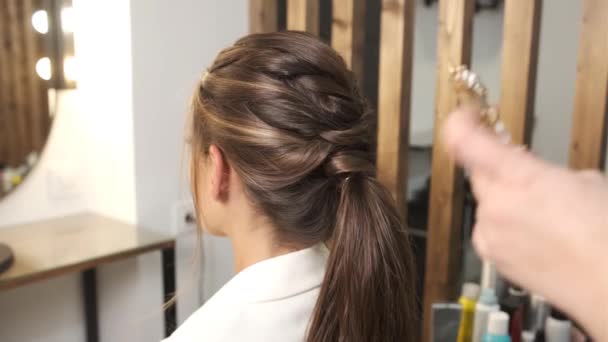 Fryzjer dołącza stylowe akcesoria do włosów na klienta podczas dokonywania jej fryzurę ślubną. — Wideo stockowe