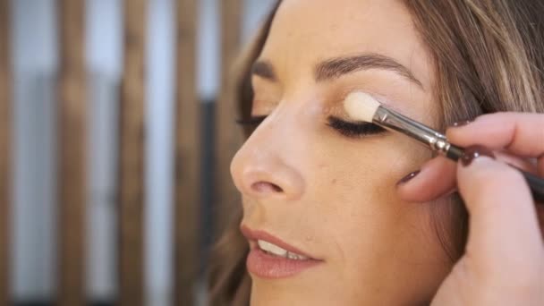 Visão de perto de uma artista de maquiagem profissional aplicando sombra nos olhos em seu cliente feminino. — Vídeo de Stock