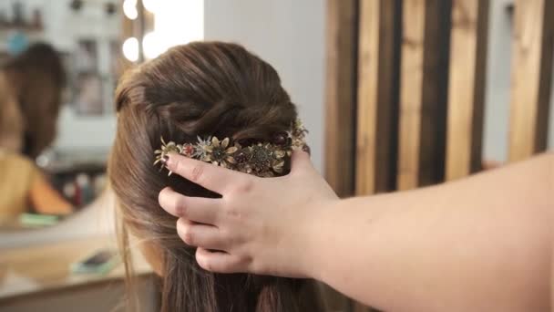 Στυλίστρια κάνει ένα χτένισμα σε μια γυναίκα πελάτη με ένα κομψό αξεσουάρ μαλλιών στο κομμωτήριο. — Αρχείο Βίντεο