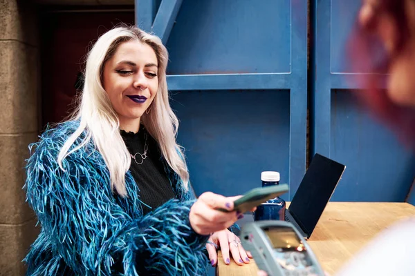 Alternatív nő fizeti a számlát mobiltelefon segítségével NFC technológia. — Stock Fotó