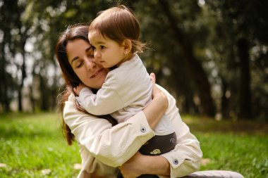 Anne, küçük kızını kucaklıyor. Doğada birlikte geçirdikleri bir günün tadını çıkarıyorlar..