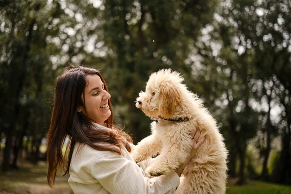 Boldog nő tartja kutyáját, miközben élvezi a szabadban töltött napot a természetben. — Stock Fotó