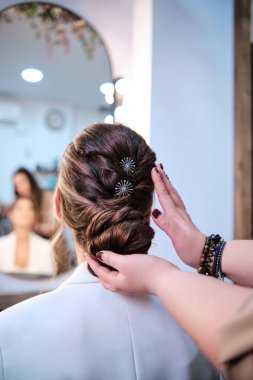 Kuaför güzellik salonundaki bir müşteri için şık bir saç stilini tamamlıyor..