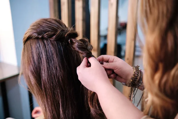 Närbild av en frisör som gör en flätad frisyr till en kvinnlig klient på frisören. — Stockfoto
