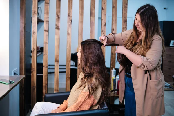 Peluquería profesional haciendo un nuevo peinado a su cliente mientras trabaja en una peluquería. —  Fotos de Stock