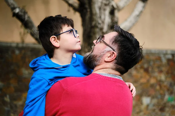 Man håller och kramar sin handikappade son medan de njuter av tid tillsammans utomhus. — Stockfoto