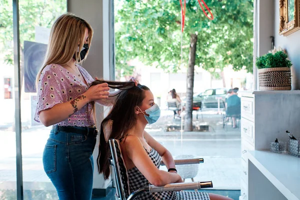 Een kapper draagt een gezichtsmasker krullen maken in de beatuy saloon - coronavirus crisis concept — Stockfoto