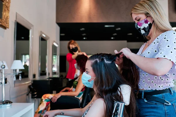 Grupp kvinnliga klienter med socialt avstånd och ansiktsmask på en frisörsalong — Stockfoto