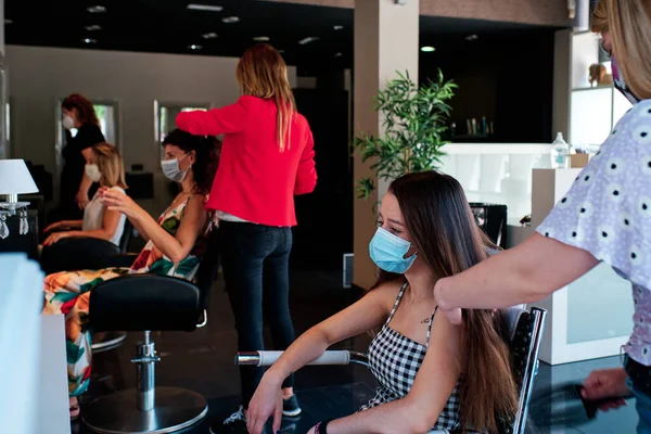 Grupp kvinnliga klienter med socialt avstånd och ansiktsmask på en frisörsalong — Stockfoto