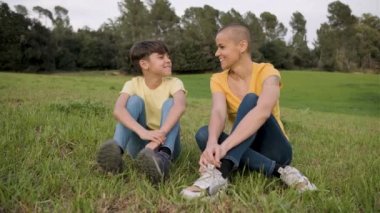 Anne ve kızı doğada çimlerin üzerinde birlikte otururken dışarıda vakit geçirmeyi seviyorlar..