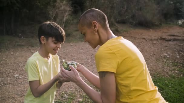 Mother showing her daughter a young tree sprout outdoors in nature. — Vídeo de Stock