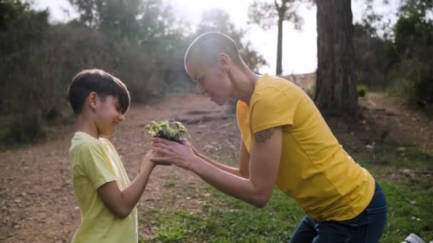 Mor visar sin dotter ett ungt träd grodd att plantera tillsammans utomhus i naturen. — Stockvideo