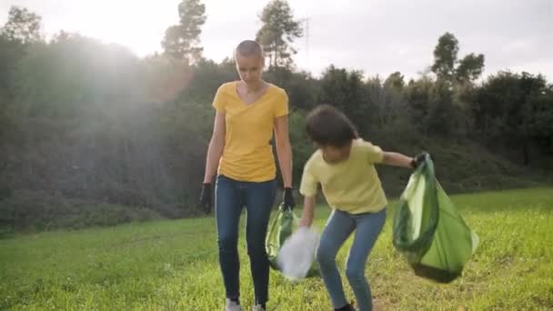 Mother and daughter collecting garbage together to keep nature clean. — Stock Video