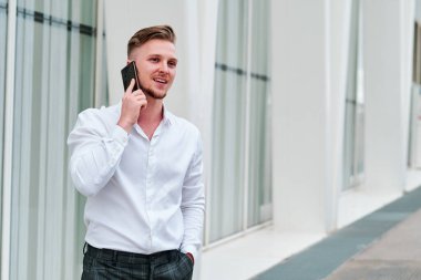 İdari işadamı ofis binasının dışında cep telefonuyla konuşuyor..