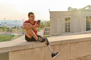 Dışarıda otururken akıllı telefonunu kullanan engelli bir adam..