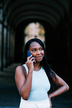 Dışarıda dikilen Afro-Amerikalı kadın telefonda konuşuyor..
