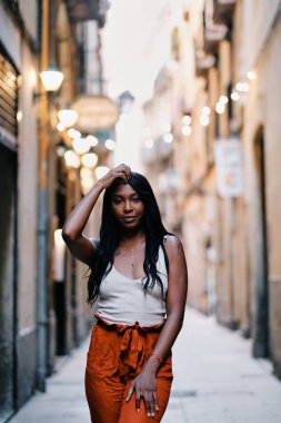 Kendine güvenen Afrikalı Amerikalı kadın dışarıda poz verirken kameraya bakıyor..