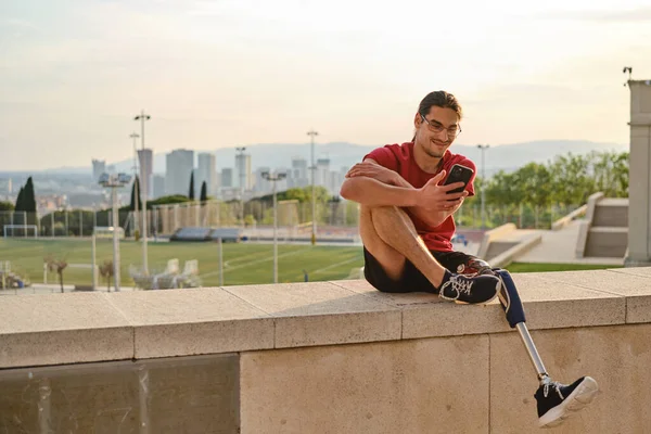 Dışarıda otururken cep telefonu kullanan engelli bir genç..