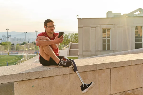 Dışarıda otururken akıllı telefonunu kullanan engelli bir adam..