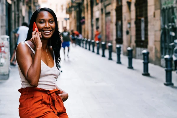 Smiling African American woman talking on the phone outdoors on the street. — Photo