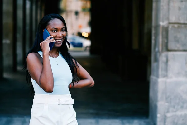 Smiling African American woman talking on the phone while standing outdoors. — Stock Fotó