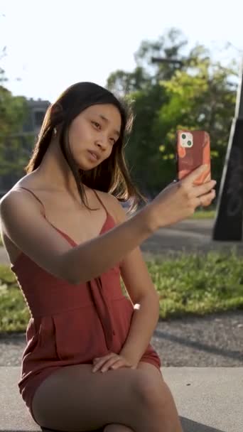 Jeune femme asiatique prendre selfies avec un téléphone mobile tout en appréciant à l'extérieur dans un parc. — Video