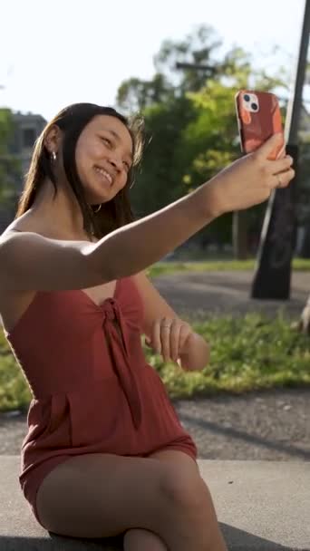 Jeune femme asiatique agitant la main et posant tout en prenant des selfies ou ayant un appel vidéo sur son téléphone mobile. — Video