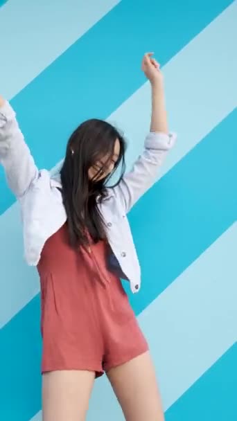 縞模様の壁にダンスをしながら楽しいアジアの女性. — ストック動画
