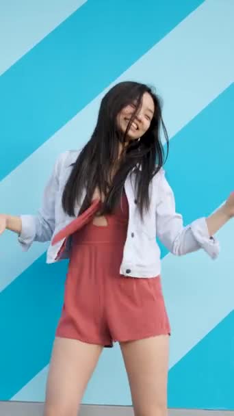 Joven mujer asiática bailando felizmente sobre una pared rayada — Vídeos de Stock