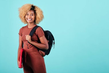 Sırtında sırt çantası taşıyan, sırtüstü sırtüstü uzanmış sırtüstü sırtüstü sırtüstü sırtüstü sırtüstü uzanmış gülümseyen afro bir kadın. Eğitim kavramı.