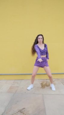 Sokakta serbest dans gösterisi yaparken kameraya bakan genç bir bayan dansçı. Müzik, dans ve gençlik kültürü.