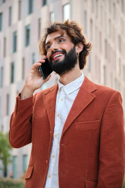 Businessman with makeup looking away and smiling while talking on the phone on the street. lgbti concept. Payment and technology concept.