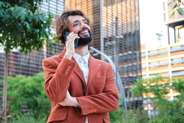 Stylish businessman with makeup smiling while talking on the phone on the street. Lgbti concept.