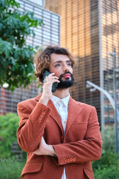 Businessman with makeup talking on the phone while standing outdoors in the financial district. Lgbti concept.