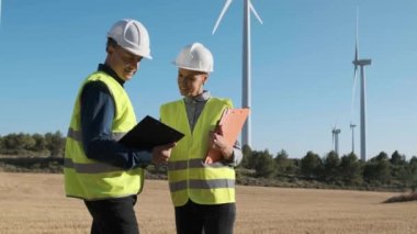 Engineer team working together in wind turbine farm. Sustainable lifestyles, renewable energy and technology concept.
