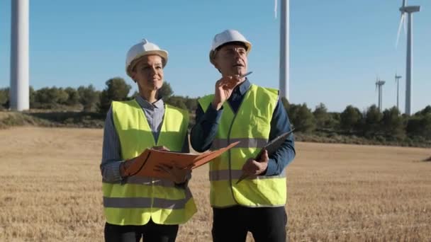 Two Engineers Talking Looking Away While Standing Wind Turbine Field — Wideo stockowe