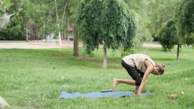 Yoga yapan bir adam parkta yoga minderiyle antrenman yaparken. Spor ve sağlıklı yaşam tarzı konsepti.