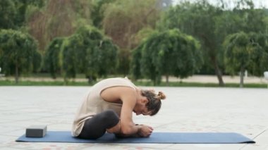 Yoga egzersizi yapan bir adam parkta bir paspasın üzerinde otururken rahatlıyor. Spor ve sağlıklı yaşam tarzı kavramı.