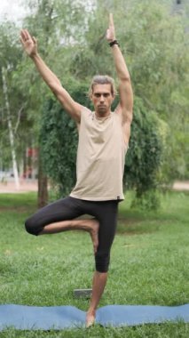 Bir adam dışarıda tek ayak üstünde dururken yoga ve denge egzersizleri yapıyor. Sağlık ve sağlıklı yaşam tarzı kavramı.