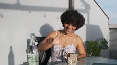 Terasta otururken cep telefonuyla video görüşmesi yapan transseksüel bir kadın. Teknoloji konsepti.