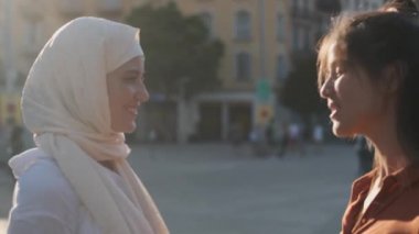 Sokakta konuşurken gülümseyen çok ırklı genç bayan arkadaşlar. Dairesel kamera hareketi.