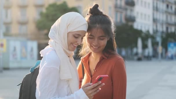 Dos Jóvenes Amigos Multiétnicos Sonriendo Mientras Usan Teléfono Móvil Juntos — Vídeos de Stock