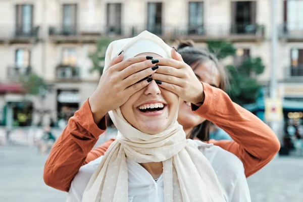 若い女性が友人の目を覆いながら通りの屋外で彼女を驚かせた 多民族友好の概念 — ストック写真