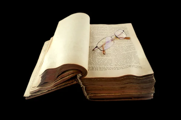 Gamla öppna ryska Bibeln med glasögon isolerad på svart bakgrund — Stockfoto